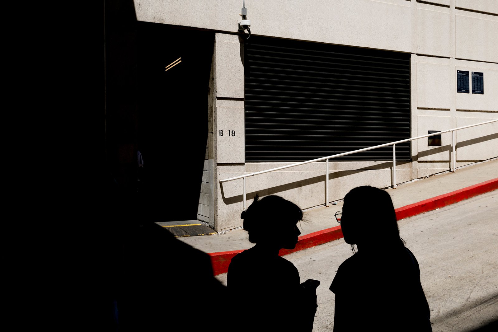 People line up on a driveway to enter a detention center located in a basement between the Edward R. Roybal Federal Building and Federal Building commonly known as "B-18" on Monday, Aug. 18, 2025 in Los Angeles, CA.