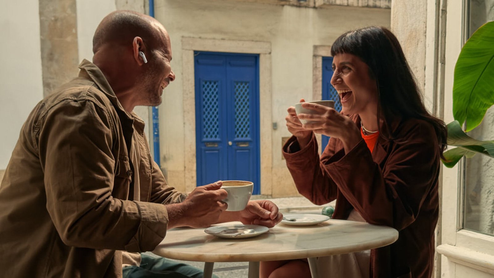 Two people talking at cafe table while wearing airpods pro 3