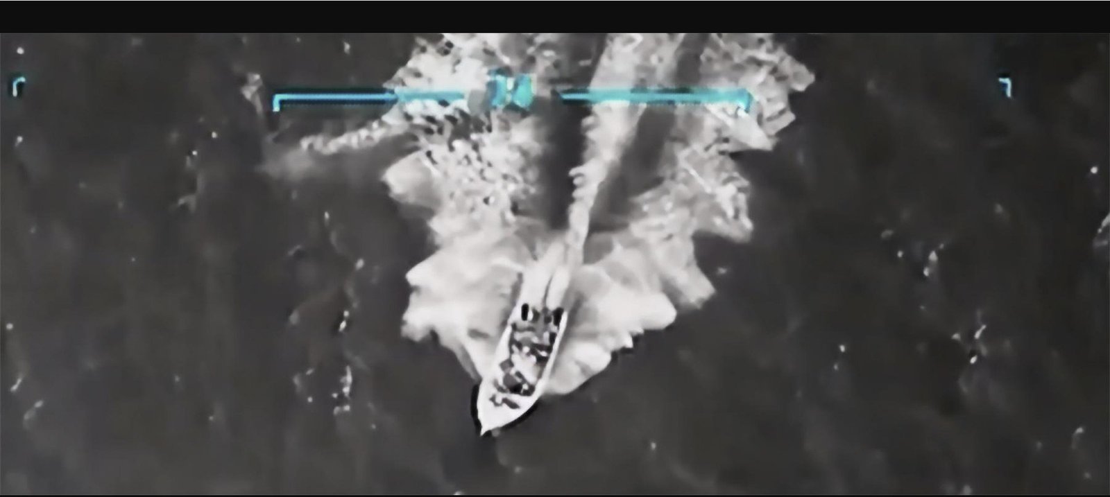 Aerial view of a speedboat navigating through water, creating waves and spray, captured in a high-contrast monochrome image.