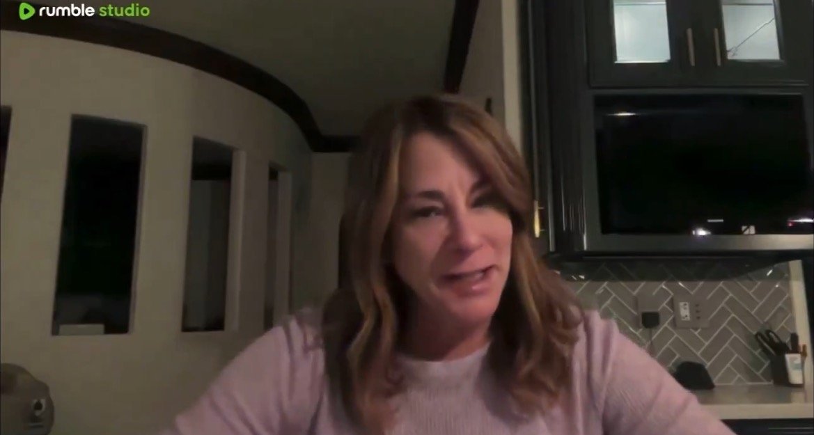 Woman speaking in a home office setting, with modern decor and a television in the background, showcasing a casual yet professional atmosphere.