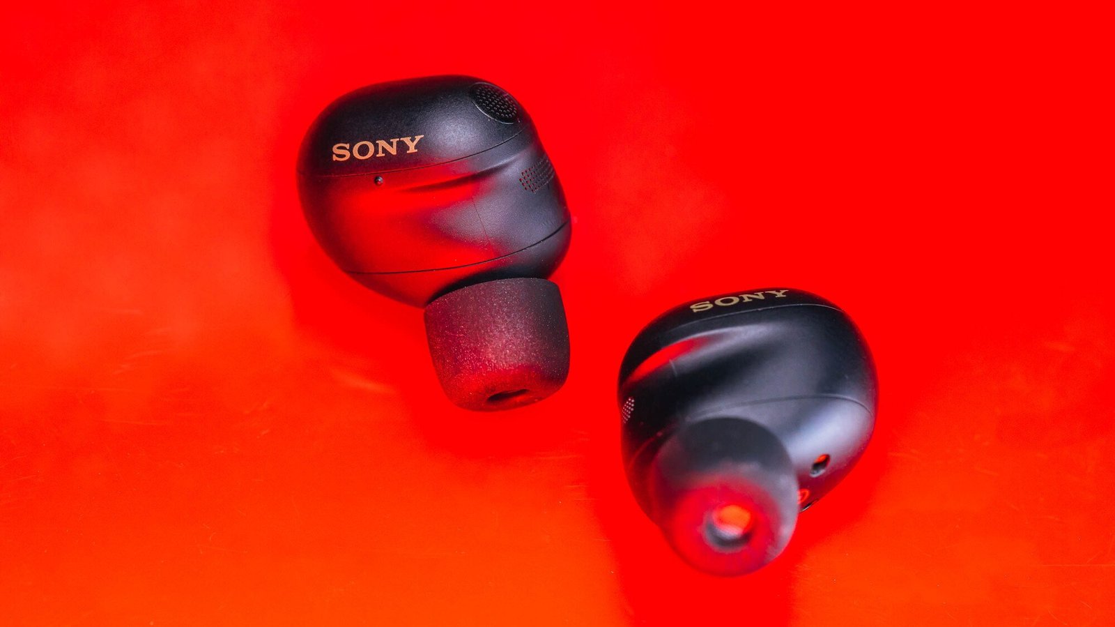 black sony xm6 earbuds on red background