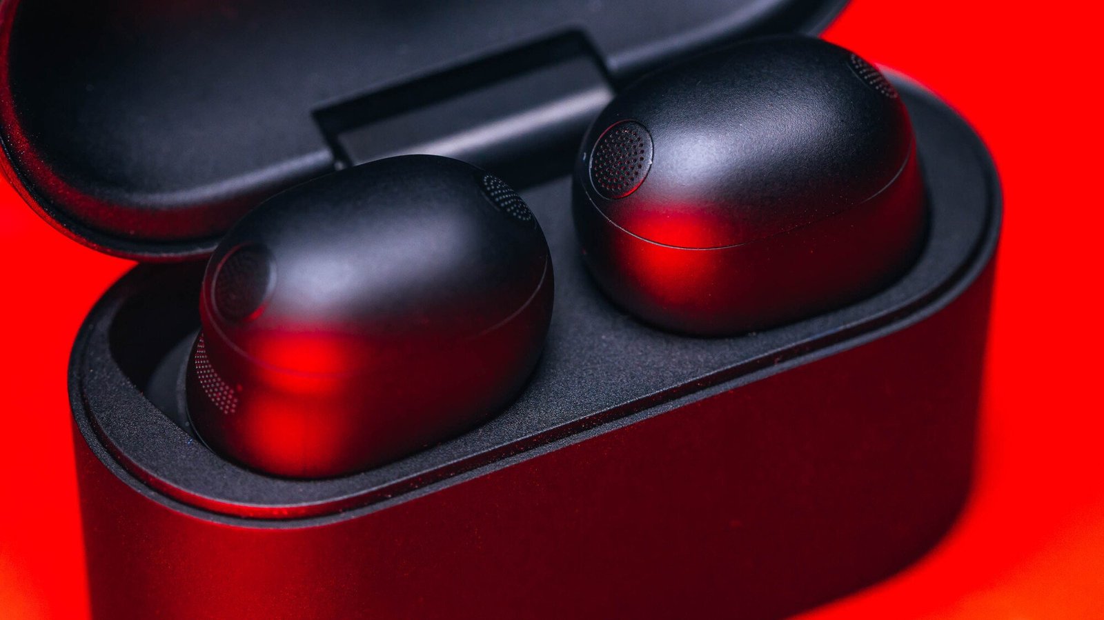 close-up on sony xm6 earbuds in case on red background