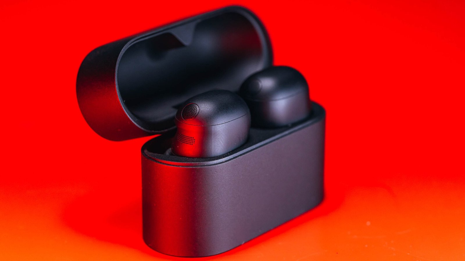 black sony wf-1000xm6 earbuds and case on red background