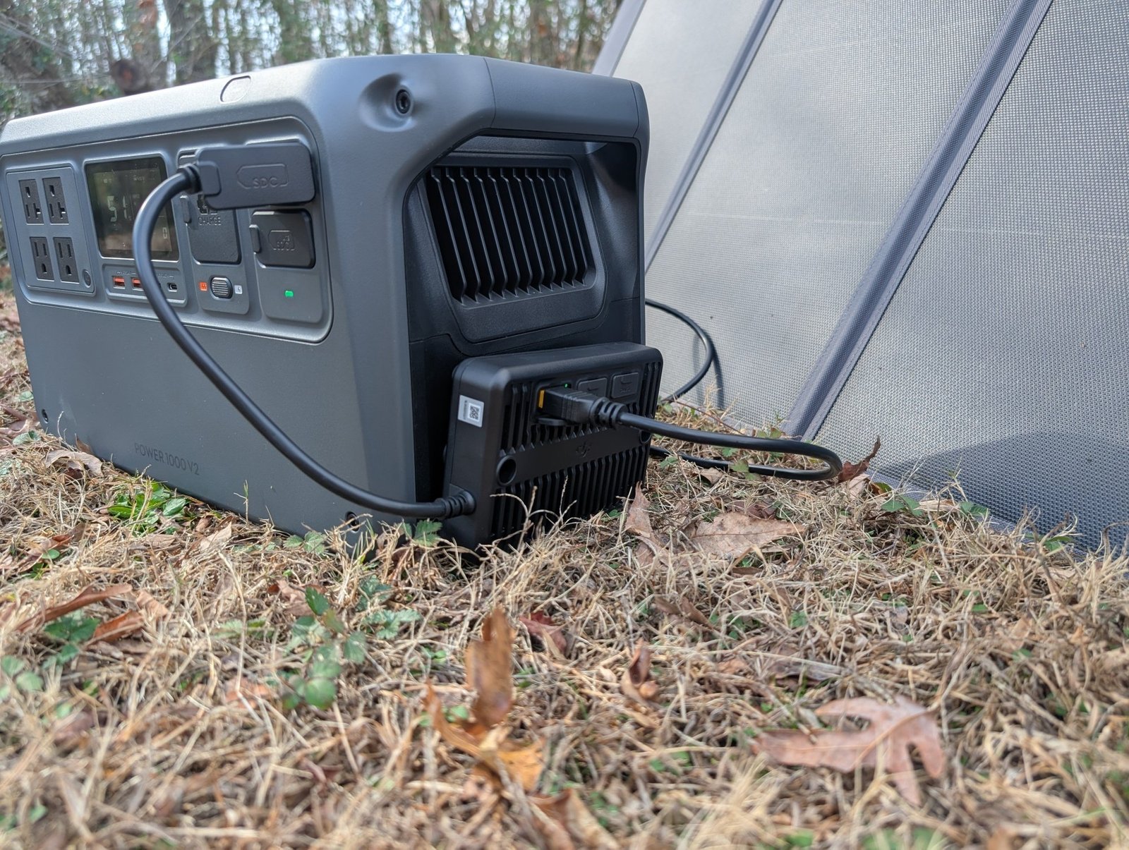 a side view of the DJI Power 1000 V2with the Power Solar Panel Adapter Module and a solar panel off to the side