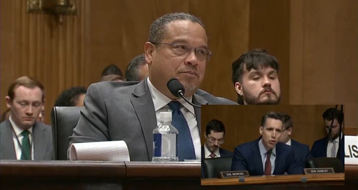Senators engaged in discussion during a congressional hearing, with one senator speaking while others listen attentively in the background.