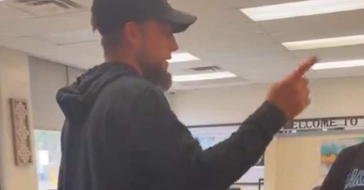 Man gesturing passionately while speaking in an indoor setting, likely during a discussion or debate.