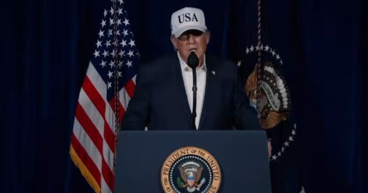 Donald Trump speaking at a podium with the presidential seal, wearing a USA hat, flanked by American flags.