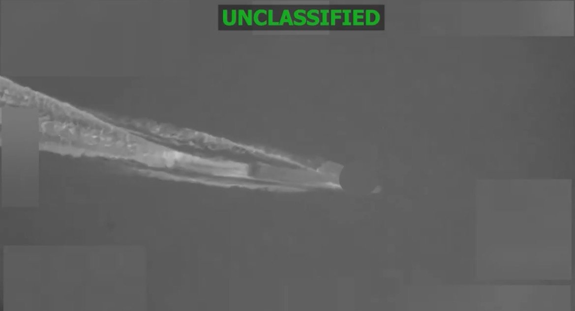 Unclassified image of an unidentified flying object emitting contrails in the sky, showcasing a distinct shape and movement pattern.