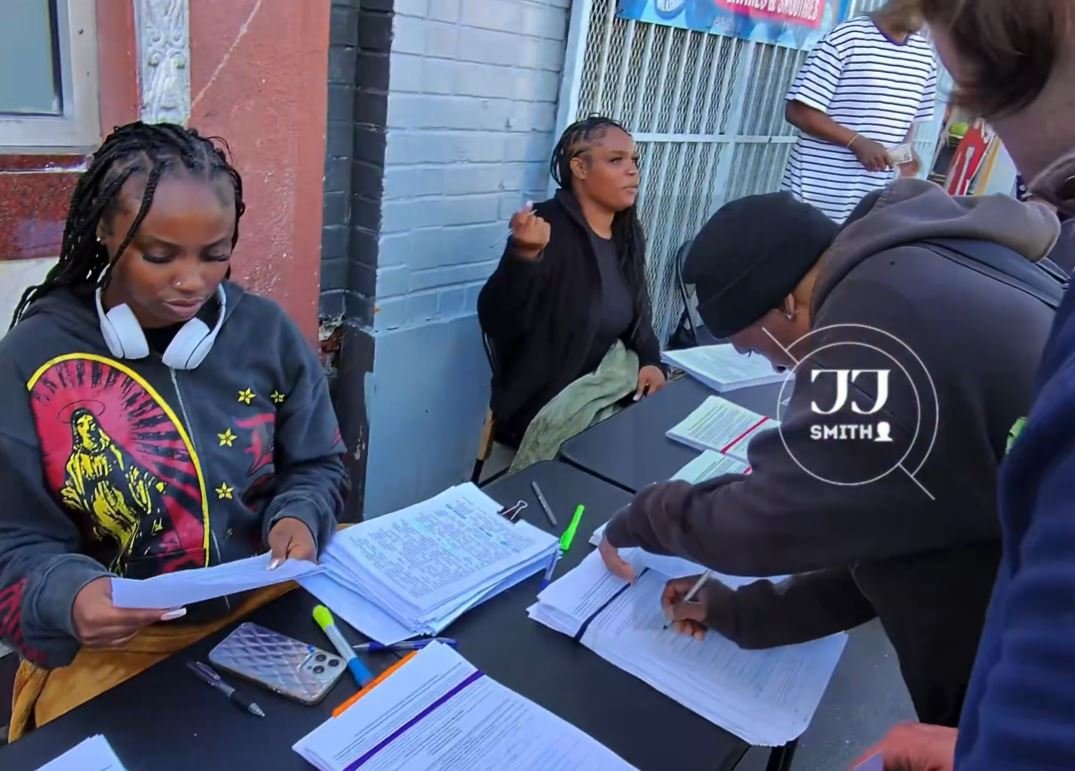 Individuals engaged in paperwork at a community event, showcasing collaboration and organization in a vibrant urban setting.