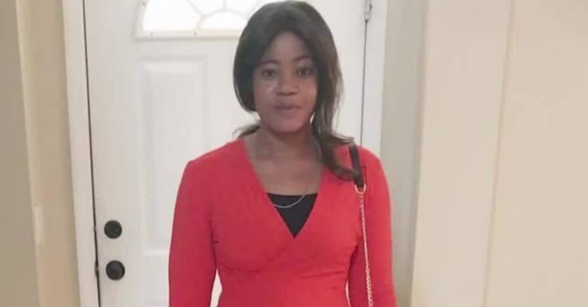 A woman wearing a red dress stands in front of a door, showcasing a casual yet stylish look.