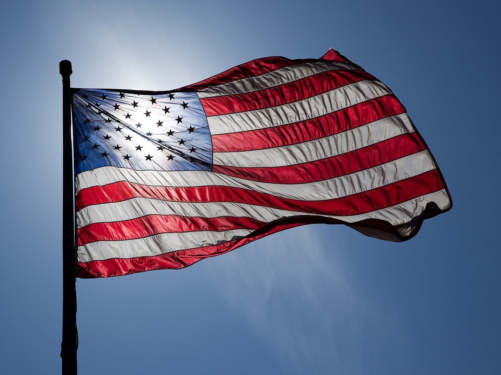 American flag waving against a clear blue sky, showcasing its vibrant red, white, and blue colors and stars.